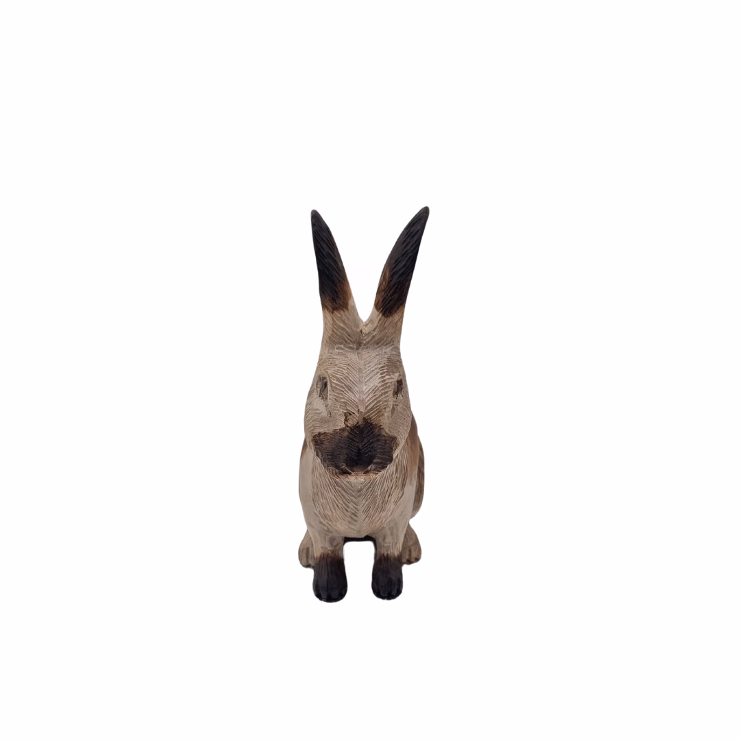 Vista frontal de un conejo de madera tallado a mano, mostrando sus orejas erguidas, detalles del hocico y textura rústica.