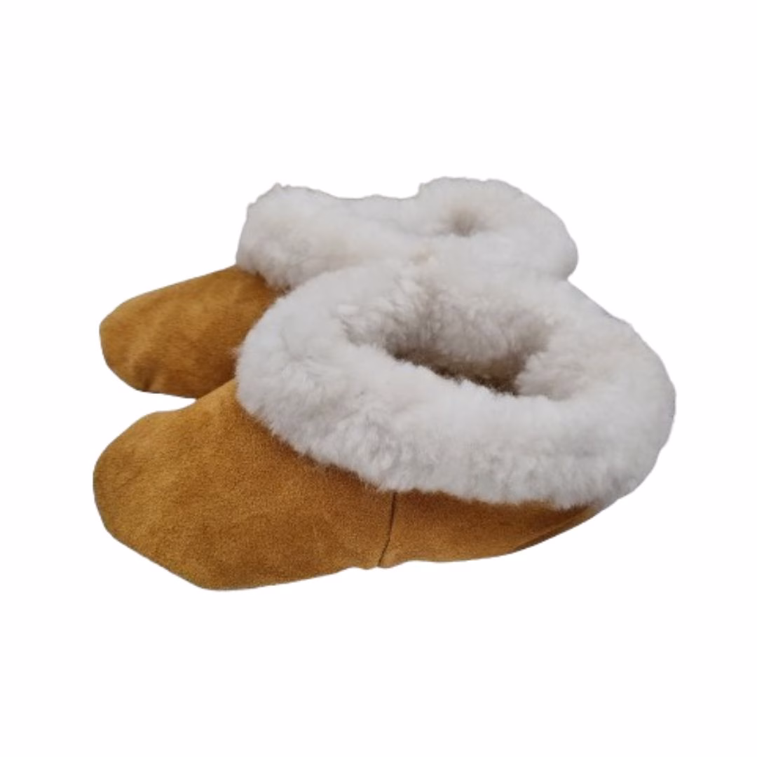 Par de pantuflas de cuero de reno color camel con un grueso borde de lana natural blanca.