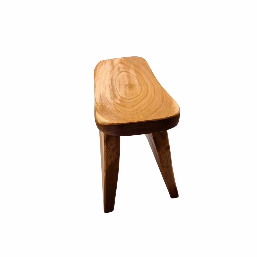 Vista superior en ángulo de un wanco de madera de raulí, destacando los anillos concéntricos tallados en el asiento curvo.