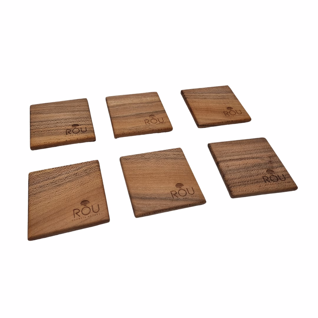 Seis posavasos cuadrados de madera de radal grabados con el logo de Rou Chile, esparcidos sobre un fondo blanco mostrando las vetas de la madera.