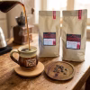 Sirviendo una taza de café en grano Pache Rojo de Guatemala junto a dos bolsas de 1 kilo marca Landorff.